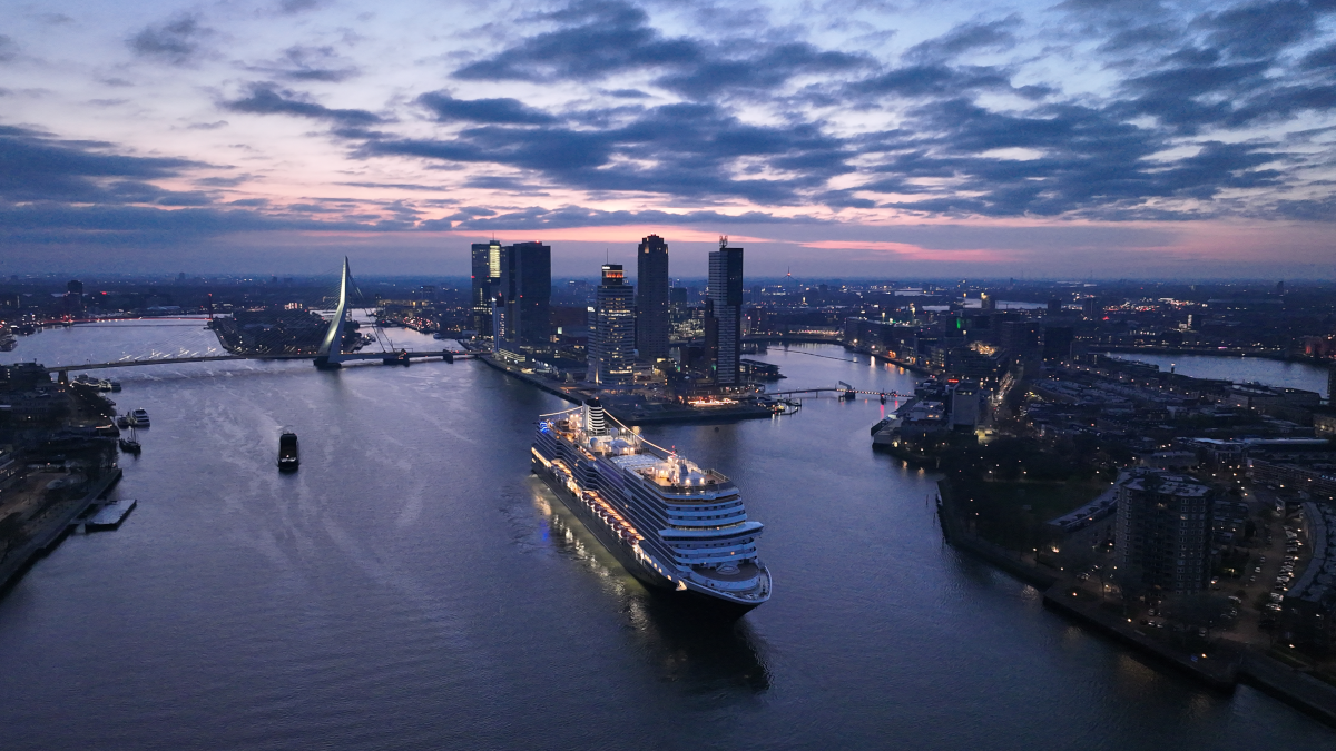 Holland America Line’s Rotterdam sailing past the city skyline at dusk
