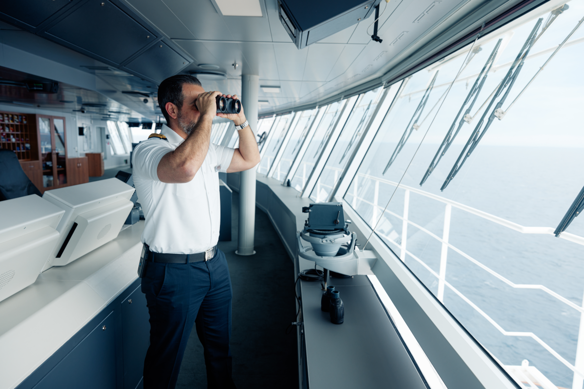 A Holland America Line bridge officer looking out to sea through binoculars
