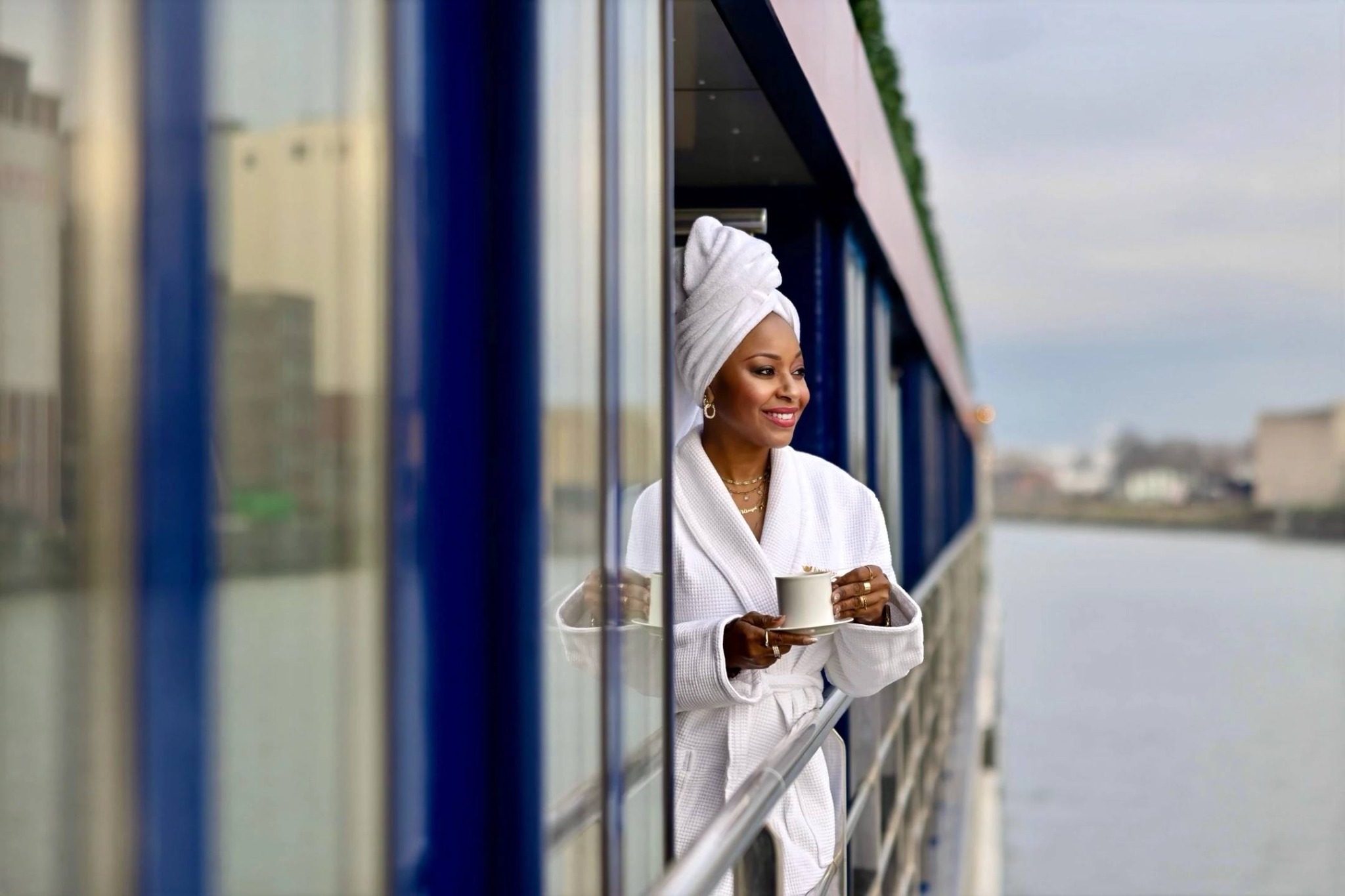 A traveler enjoying coffee from the front-row view of her river-cruise balcony