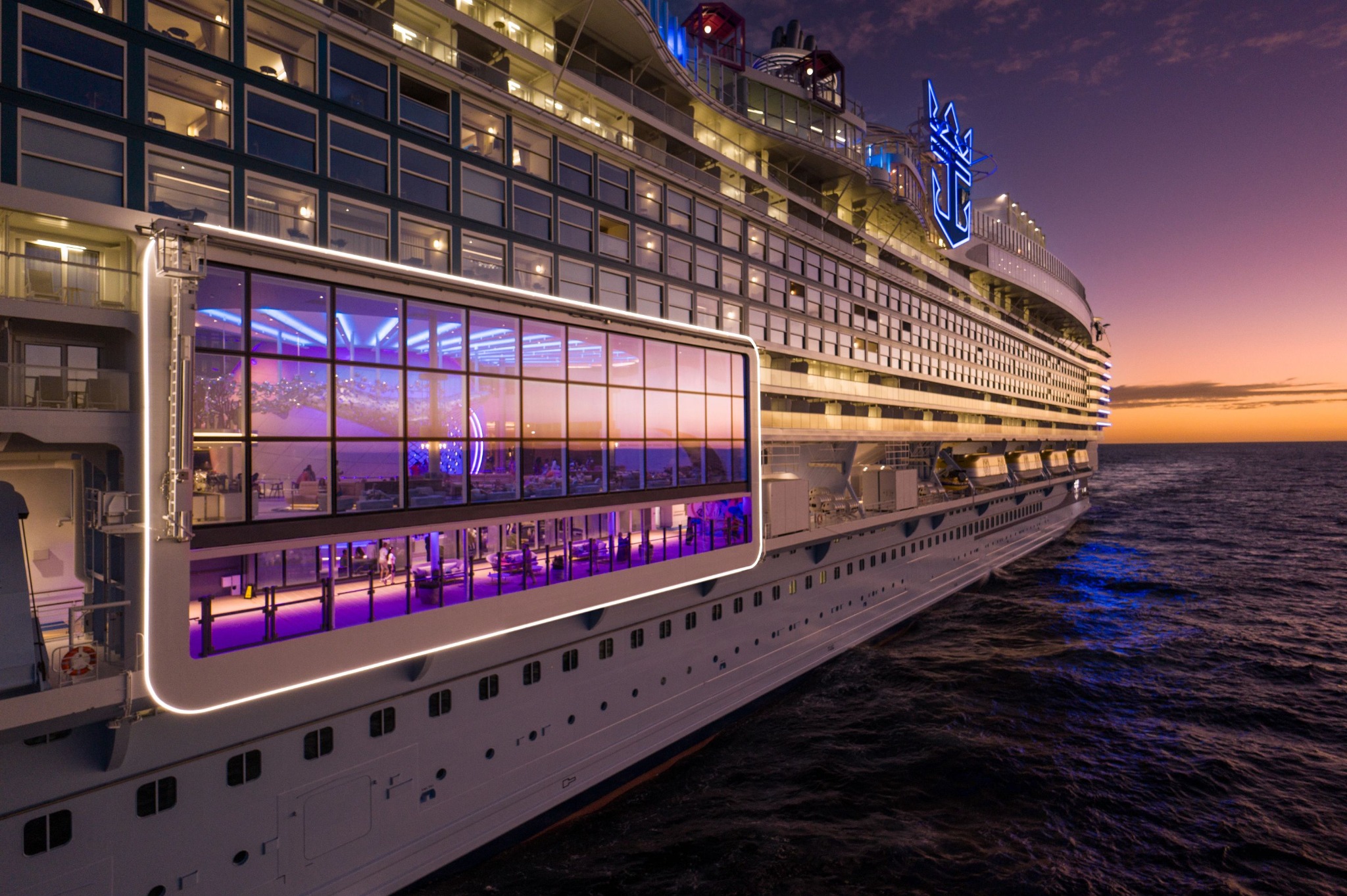 An illuminated Royal Caribbean cruise ship at sea at sunset
