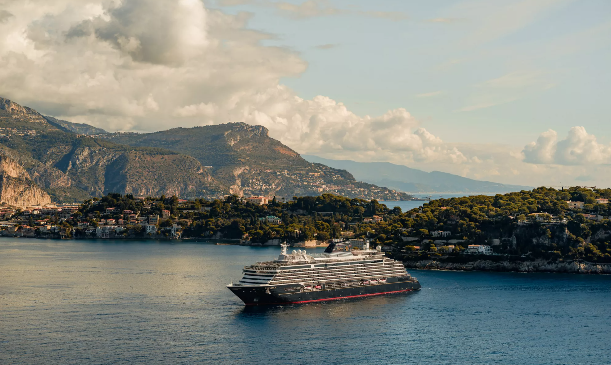 An Explora Journeys ship sailing along a mountainous coast