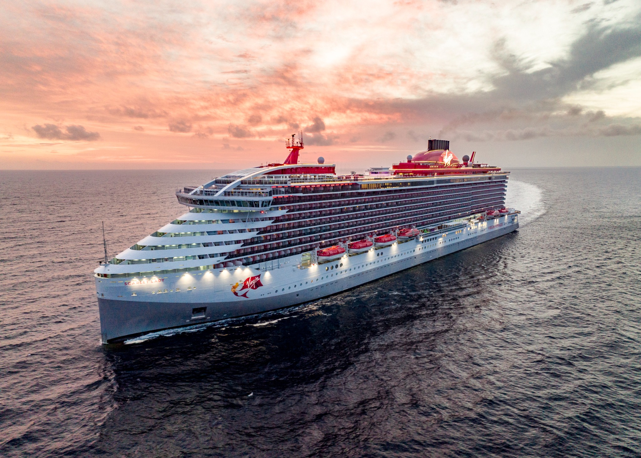 Virgin Voyages' Scarlet Lady sailing at sunset