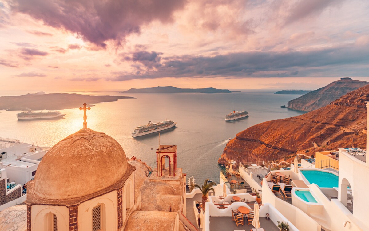 Cruise ships anchored beneath a colorful Santorini sunset